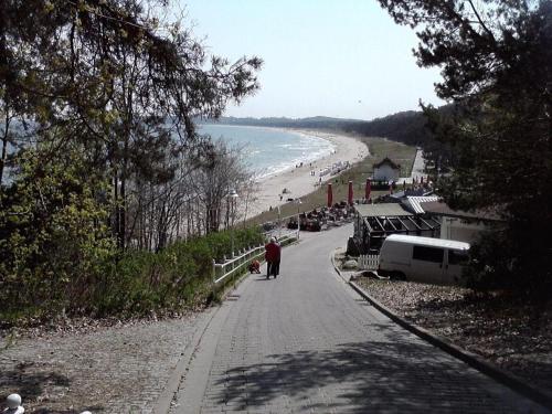 a person walking down a road next to a beach at 2-Zimmer-Ferienwohnung-in-Sellin-auf-Ruegen-direkt-an-der-Seeparkpromenade in Ostseebad Sellin