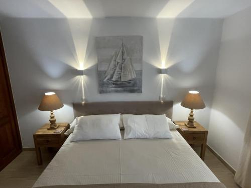 Un dormitorio con una gran cama blanca con dos lámparas. en Las Brisas Villa 106, en Playa Blanca