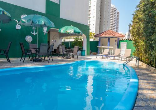 a pool with chairs and umbrellas next to a building at Hotel Nacional Inn Guarujá in Guarujá