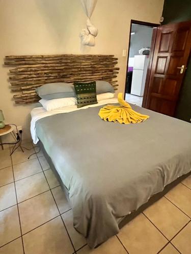 a bedroom with a large bed with a yellow blanket on it at Hello Kruger Hideaway in Marloth Park