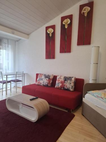 a living room with a red couch and flowers on the wall at Exclusive Apartments in Bietigheim-Bissingen