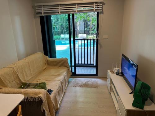 Una sala de estar con un sofá y un televisor. en อมรรัตน์Room ดอนเมือง, en Samut Sakhon