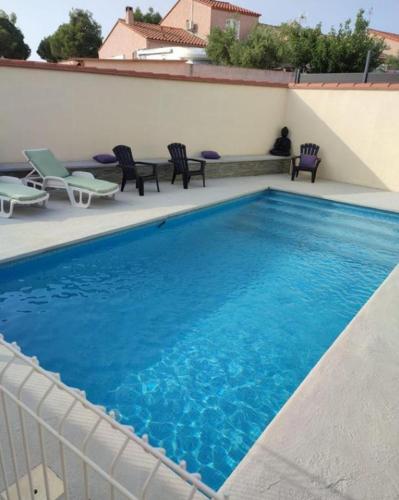 une grande piscine bleue avec des chaises et des chaises dans l'établissement Villa luxe, avec jardin, piscine privée, proche de la mer, à Saint-Cyprien