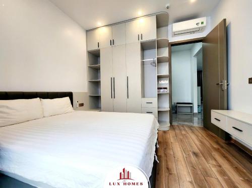 a bedroom with a large white bed and a bathroom at The LuxHomes Apartment ᵀᴹ I HOT Độc Đáo Nhất Vinhomes Marina in Hai Phong