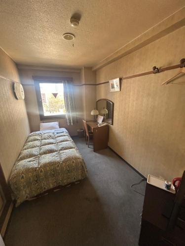 a bedroom with a bed and a desk and a window at Business Hotel Nakayama in Nagoya