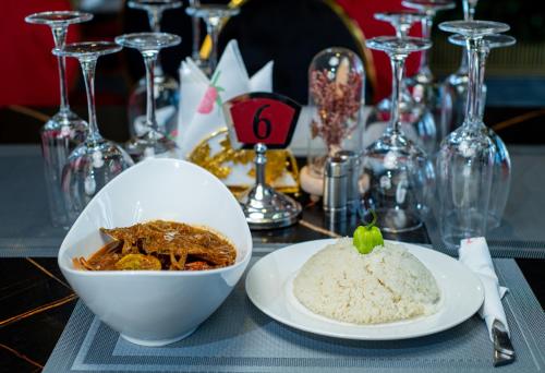 a table with a bowl of rice and a plate of food at Hôtel ZUMAH in Ouagadougou