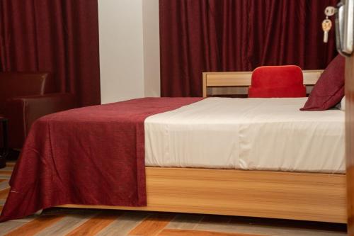 a bedroom with a bed and a red chair at Hôtel ZUMAH in Ouagadougou