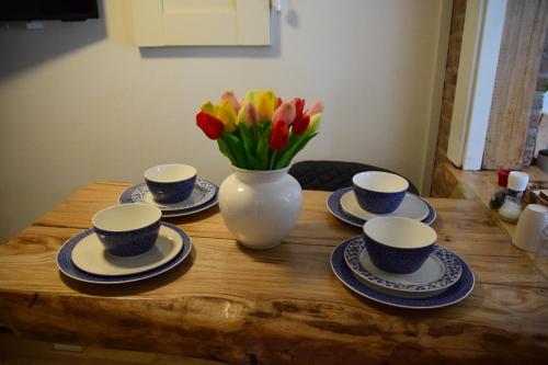 a table with four cups and a vase with flowers at B&B CaSandra in Volendam
