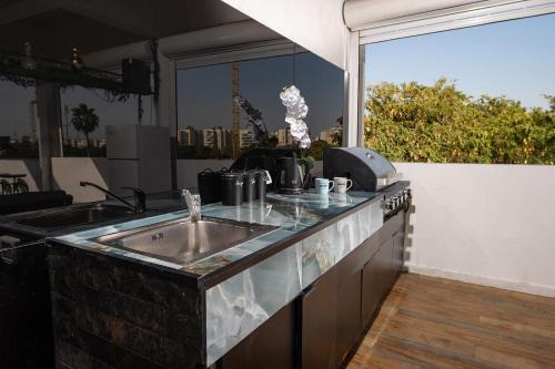 a kitchen with a sink and a large window at הפנטהאוז של תל אביב - דירות סטודיו מהממות ופנטהאוז משגע עם ג'קוזי פרטי! in Tel Aviv
