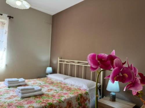 a bedroom with a bed and a vase with purple flowers at Casa Archi in Cefalù