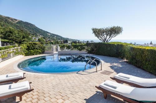 a swimming pool with two lounge chairs next to a resort at Jumeirah Capri Palace in Anacapri