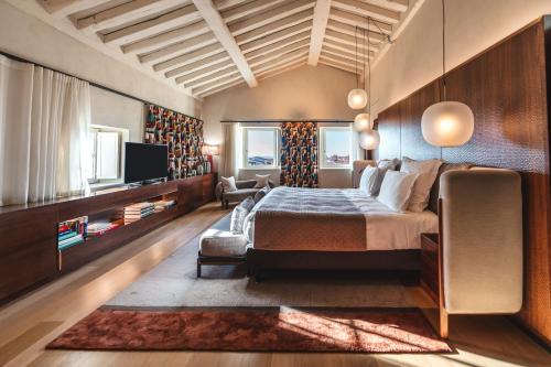 une chambre avec un lit, un canapé et une télévision dans l'établissement Hôtel de Pavie, à Saint-Émilion