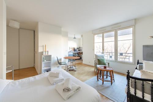 - une chambre avec un lit blanc, une table et des chaises dans l'établissement Dames - Studio lumineux Gare Saint-Lazare, à Paris