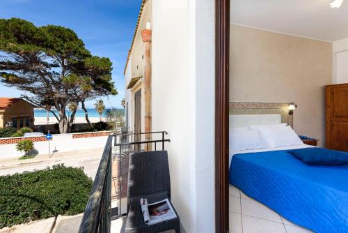 a bedroom with a bed and a balcony with a view at Hotel La Darsena in San Vito lo Capo