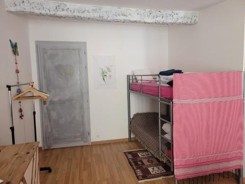 Cette chambre comprend un lit superposé avec des draps roses et une porte. dans l'établissement Grand studio chez Lucie, à Cotignac