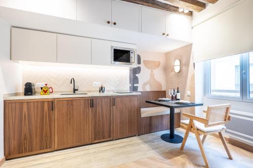 une cuisine avec des placards en bois et une table avec une chaise dans l'établissement HolidaysInParis - Bourg Tibourg, à Paris