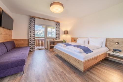 a bedroom with a large bed and a couch at Hotel Winterer in Schladming
