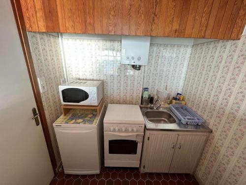 une petite cuisine avec un micro-ondes et un évier dans l'établissement Studio plage à St Gilles - accès direct - FR-1-324-104, à Saint-Gilles-Croix-de-Vie