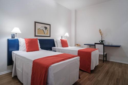 a hotel room with two beds and a desk at Hotel Normandie in Sao Paulo
