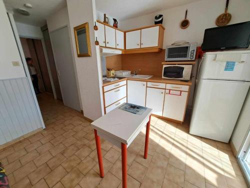 Elle comprend une petite cuisine équipée d'un réfrigérateur blanc et d'une table. dans l'établissement Appartement 2 pièces RDC avec Parking, Terrasse - FR-1-326-439, à Le Castellas