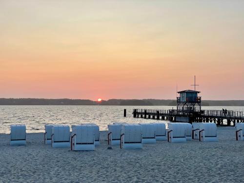 eine Gruppe Liegestühle am Strand mit einem Pier in der Unterkunft Ferienapartment schön hier in Glücksburg