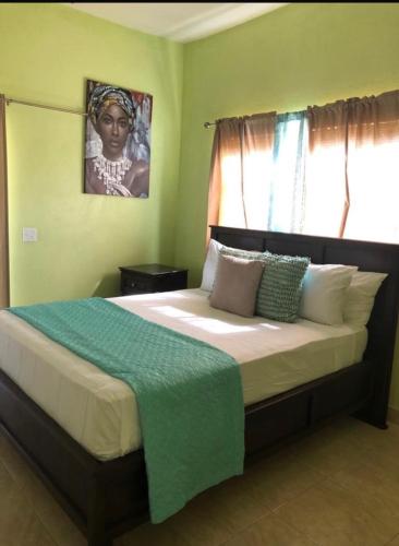 a bedroom with a bed with a green blanket on it at J&L beachfront bliss steps to sand an sunset views in Rolleville