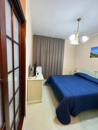 a bedroom with a blue bed and a desk with a television at Hotel Geranio Rosso in Stintino