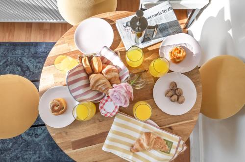 a wooden table with plates of food and orange juice at Apartment Big Ben, 10 mins to London Bridge, 5 min Croydon, 30 min Airport in London