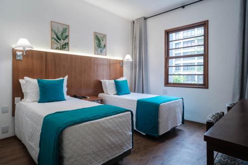 a hotel room with two beds and a window at Hotel Normandie in Sao Paulo