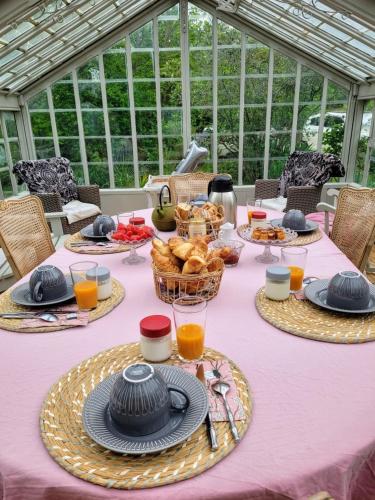 a table with a pink table cloth with baskets of food at Le Clos de l'Ambre in Divajeu