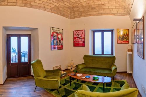 a living room with two green chairs and a table at Palazzo D'Alessandro Wunderkammer & Suites B&B di charme in Caporciano