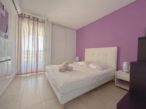 une chambre avec un lit blanc avec un mur violet dans l'établissement Fréjus 2 pièces avec Terrasse, proche des Plages, à Fréjus
