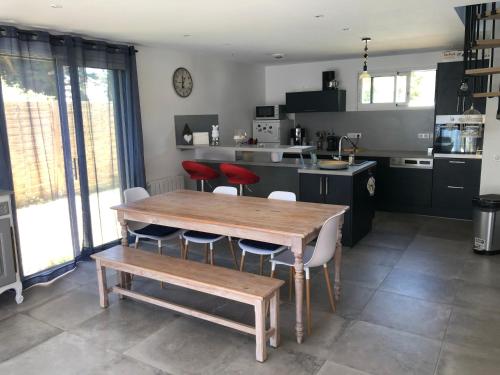 une cuisine avec une table en bois et des chaises rouges dans l'établissement Maison sur jardin clos à 100m de la plage, à l'Île-Tudy