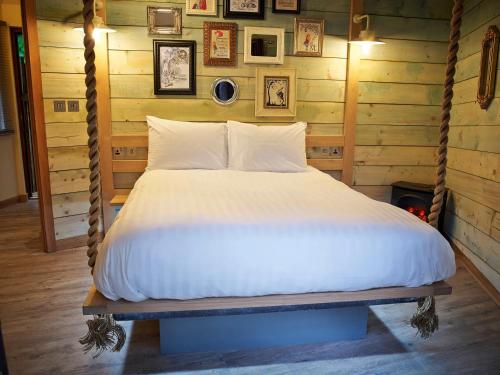a bed in a room with a wooden wall at Blackwood Forest Cabins - Forest Holidays in Popham