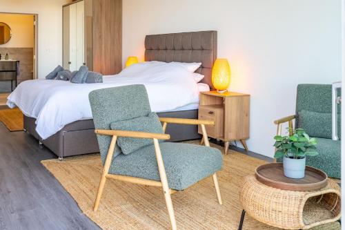 a bedroom with a bed with two chairs and a table at The Ark 4 in Southwold