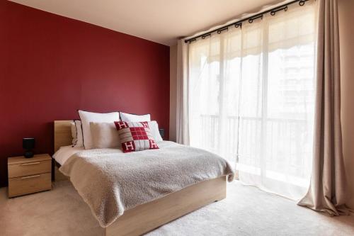 - une chambre avec des murs rouges et un lit avec une fenêtre dans l'établissement Trocadéro Love, à Paris