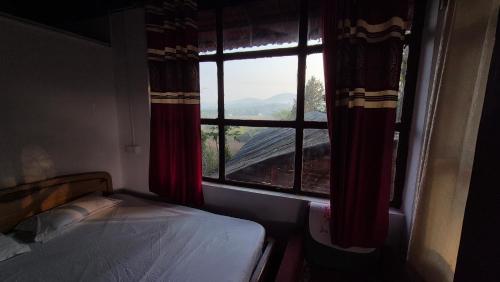 a bedroom with a window with a view of a mountain at Coorg Tribal Land homestay in Kushālnagar