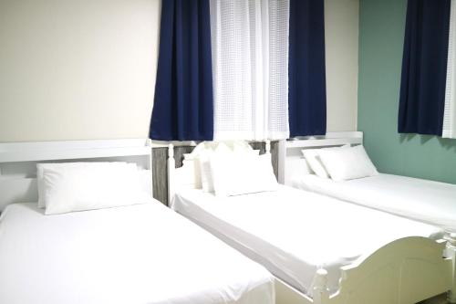three beds in a room with blue curtains at Mr. Kim Guesthouse in Incheon