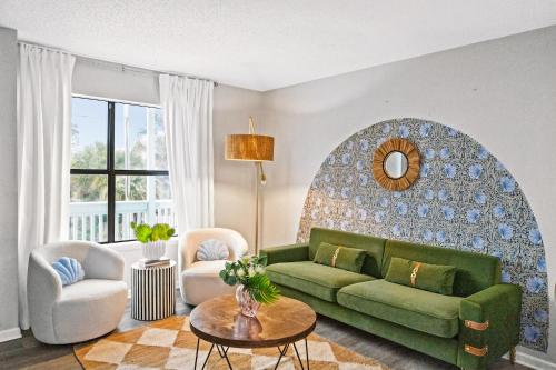 a living room with a green couch and a table at Waterfront Condo - Canal Views - Walk to Beach in Gulf Shores
