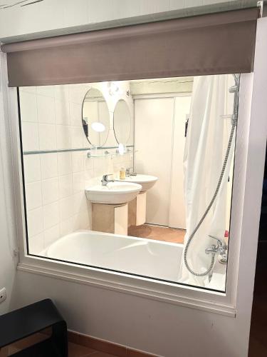 une salle de bain avec une baignoire, un lavabo et un miroir dans l'établissement Les terrasses de Lure, à Villemus