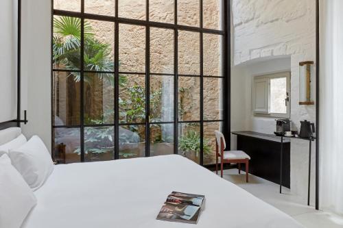 a bedroom with a white bed and a large window at Palazzo Petrvs in Orvieto