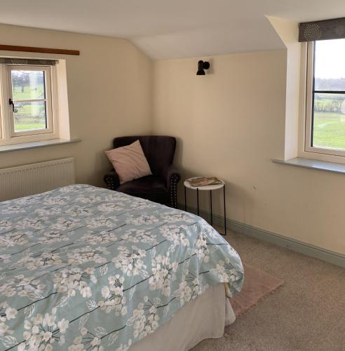 a bedroom with a bed and a chair and windows at Farmhouse studio near Shrewsbury in Shrewsbury