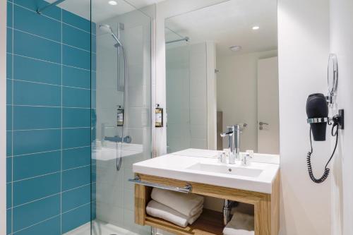 a bathroom with a sink and a shower and a phone at Akena Nantes Rezé Aéroport in Rezé