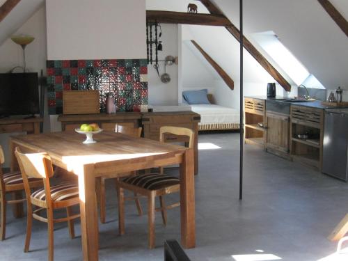 une cuisine et une salle à manger avec une table et des chaises en bois dans l'établissement Loft du Petit Bois, à Château-la-Vallière