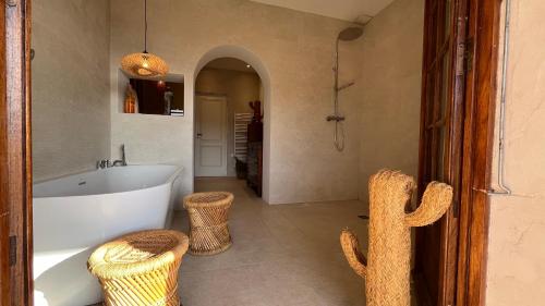 La salle de bains est pourvue d'une baignoire et de deux tabourets en osier. dans l'établissement Nouveau Le Mas des Serens, à La Gaude