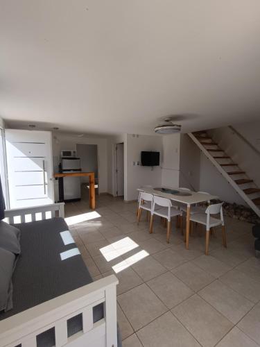 a living room with a table and chairs and a staircase at Aire de las Sierras in Embalse