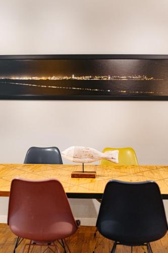 a table with three chairs and a picture on the wall at Joli Guesthouse in Maputo