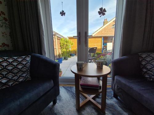 a living room with a couch and a table and a window at Flower Garden Studio in Sheringham-Cycle friendly in Sheringham