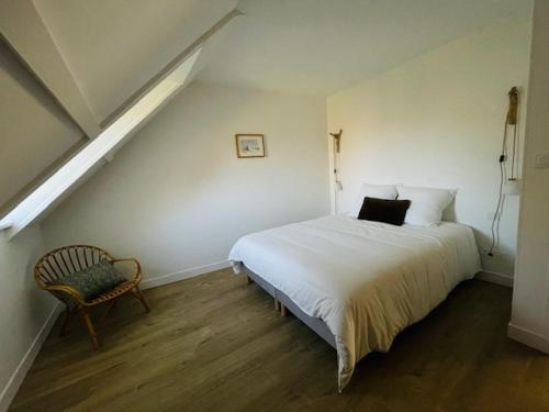 une chambre avec un lit blanc et une chaise dans l'établissement L'Inattendue, à Saint-Vaast-la-Hougue