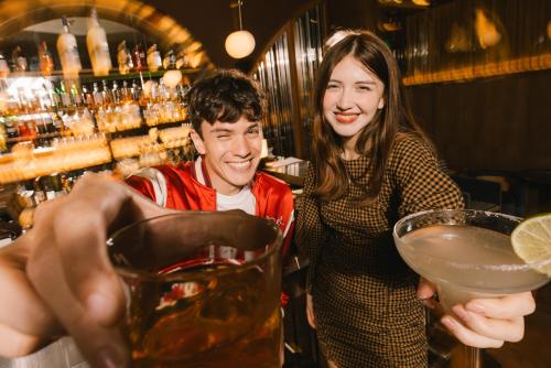 a man and a woman standing in a bar with a drink at Public House Bangkok, a Member of Design Hotels in Bangkok